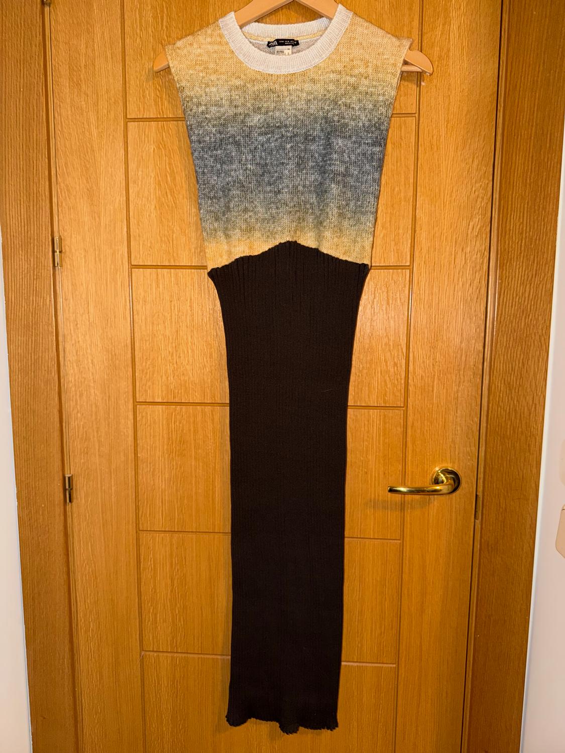 Vestido sin mangas en degradado de colores sobre una puerta de madera. Parte superior en tonos beige y azul, inferior negra.