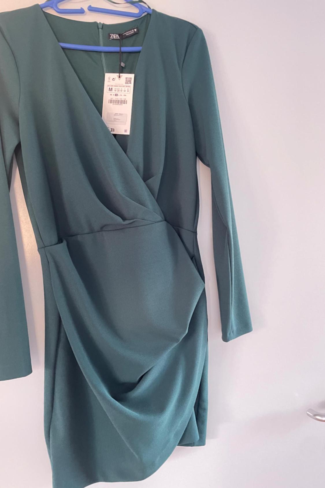 Front view of a green dress with a crossover neckline and long sleeves.