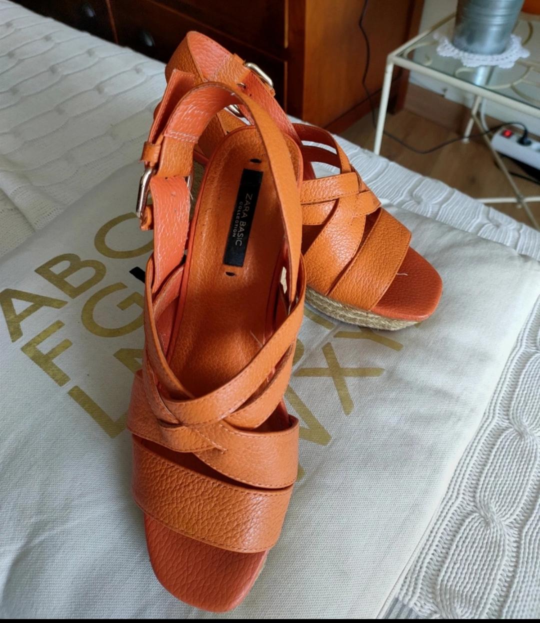 Detail of orange sandals with criss-cross straps and 'ZARA BASIC' label.
