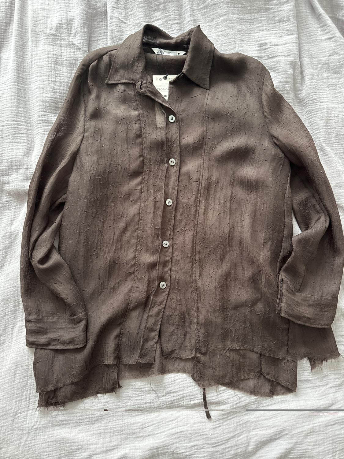 Brown crinkle-effect fabric shirt with white buttons, on a white surface. Visible label on the collar.