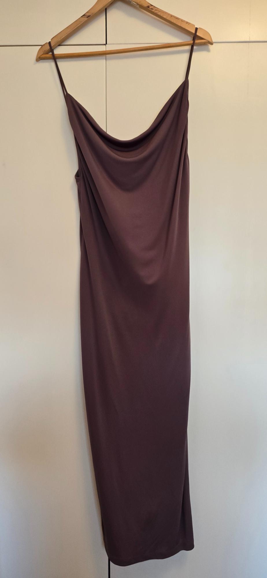 Plum long slip dress with a cowl neckline and delicate straps, hanging on a wooden hanger on a white wardrobe.