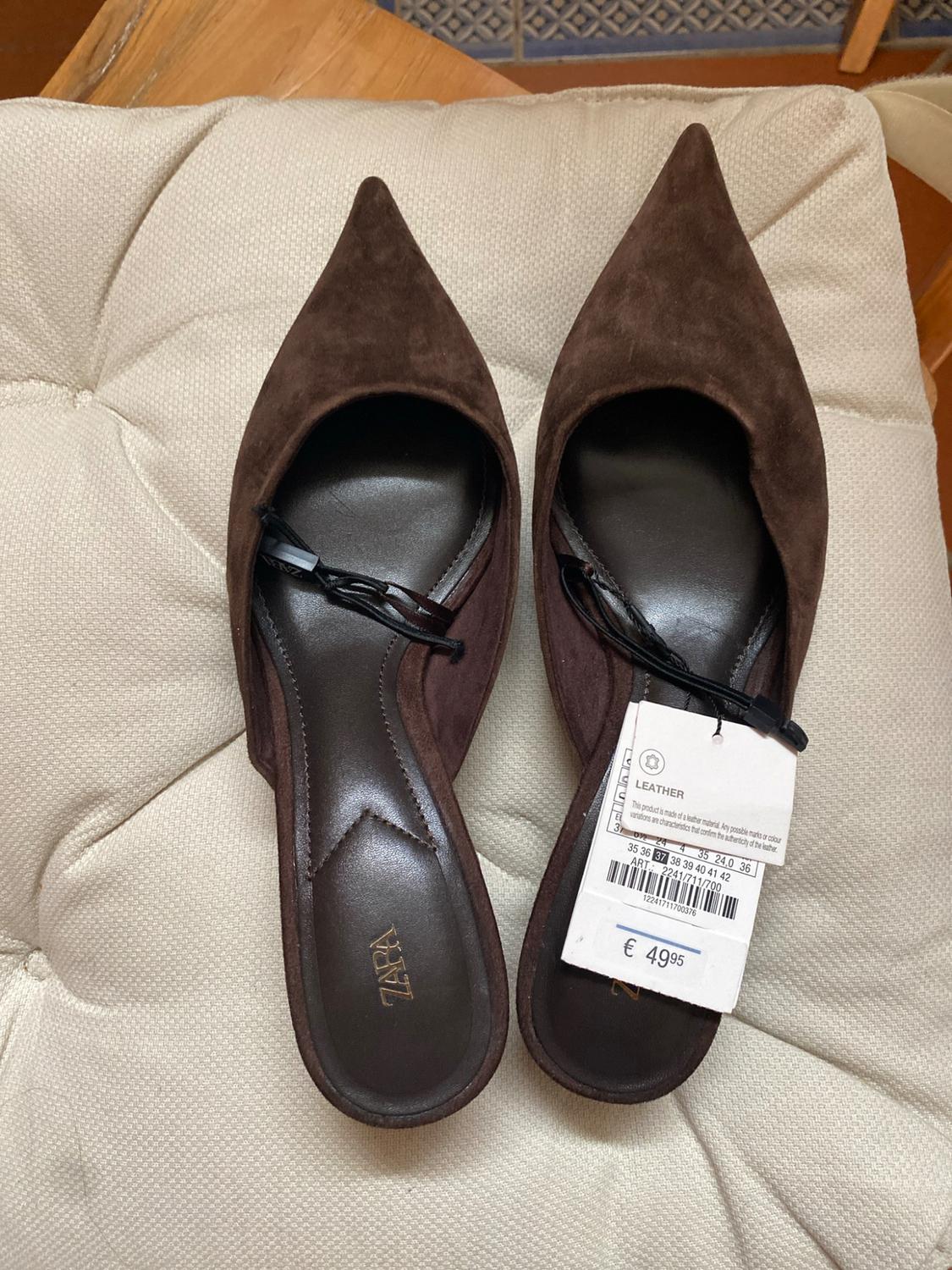 Brown pointed-toe suede slingback shoes on a cushion. Visible text: ZARA, LEATHER, ART.: 2241/711/700, € 49.95.