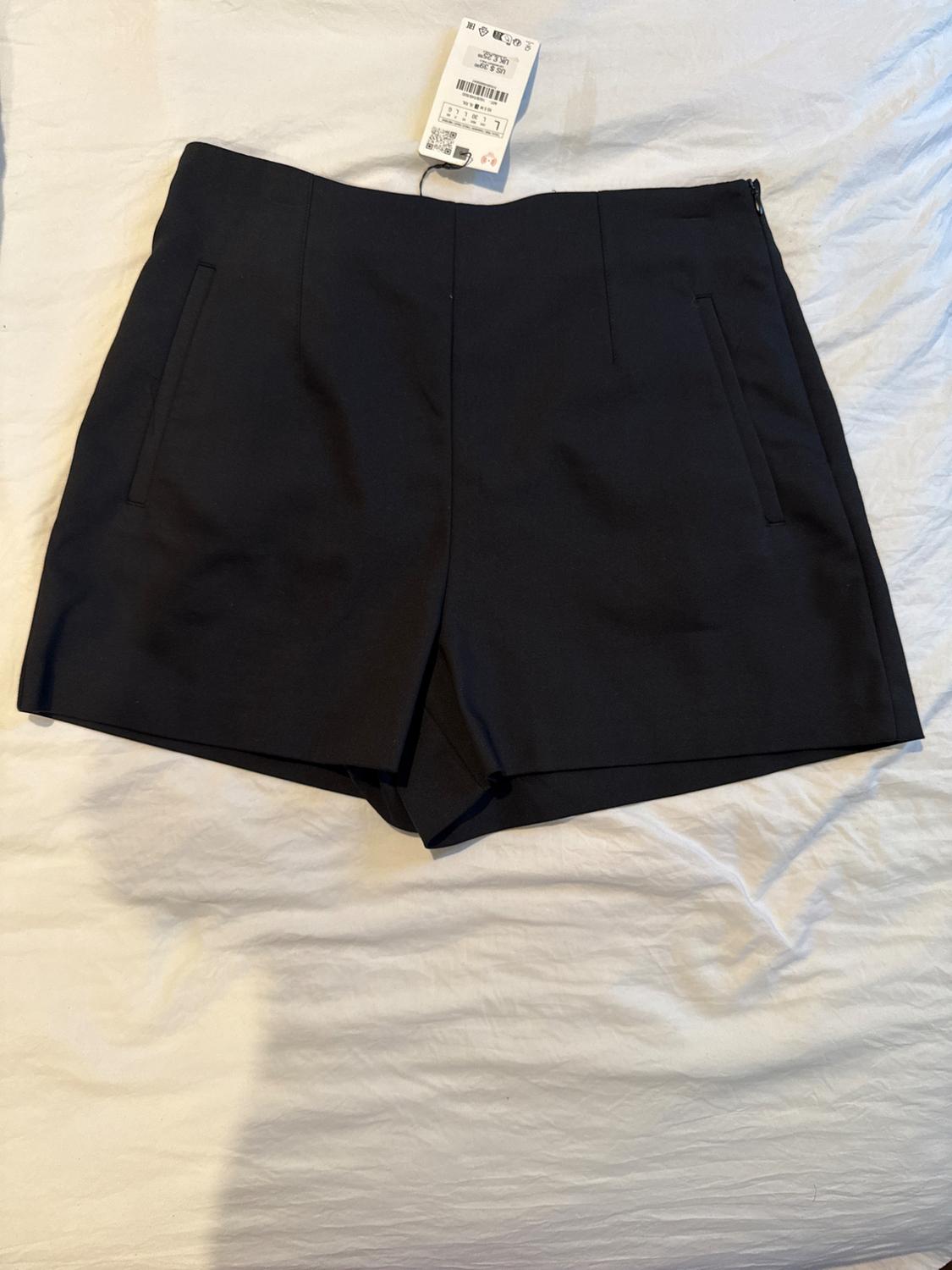 Front view of black shorts with side pockets and visible label.