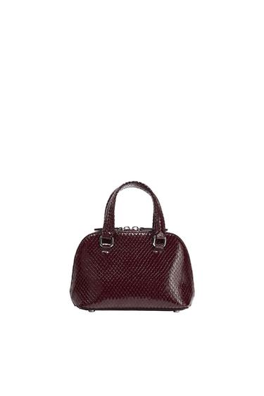 Small burgundy handbag with a shiny snake-texture finish, short handles, a zipper closure, and a white base.