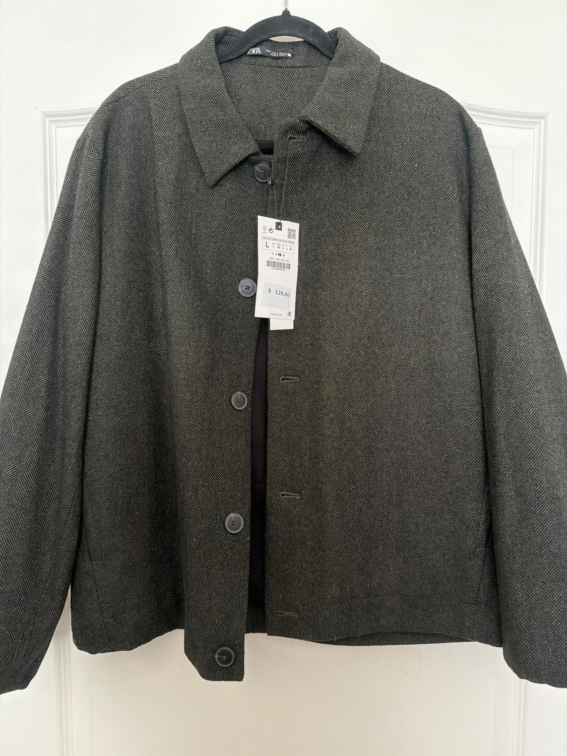 Gray jacket with large buttons on a black hanger, with a price tag of $129.00. White background.