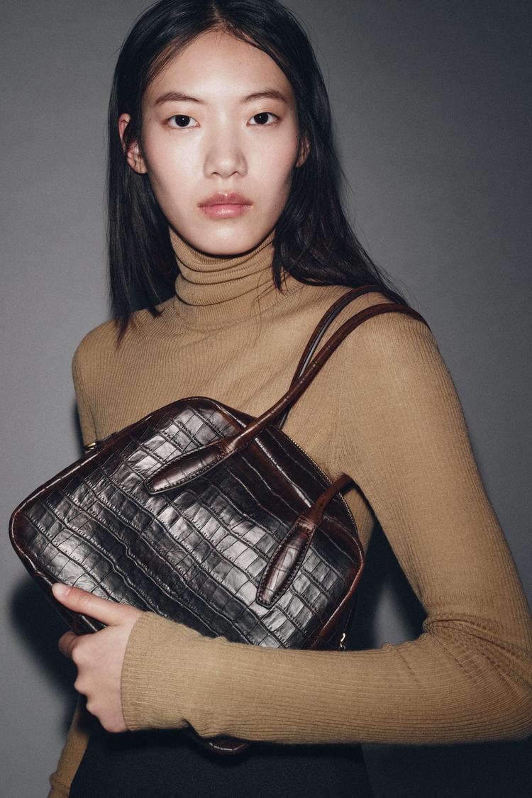 Detail �okol�dov� kabelky s reli�fem a dvojit�m uchem. Viditeln� zap�n�n� na zip.