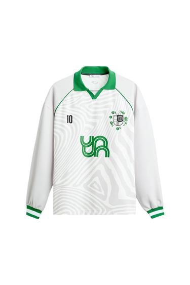 White sports t-shirt with a green collar and cuffs, number 10 and green logo on the front, with a wavy line design.