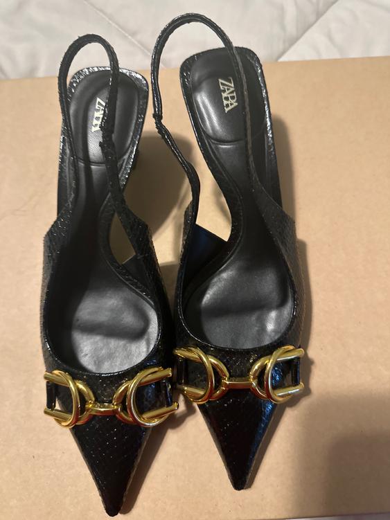 Textured black high-heeled shoes with gold details on the toe and thin straps. "ZARA" brand visible on the insole.