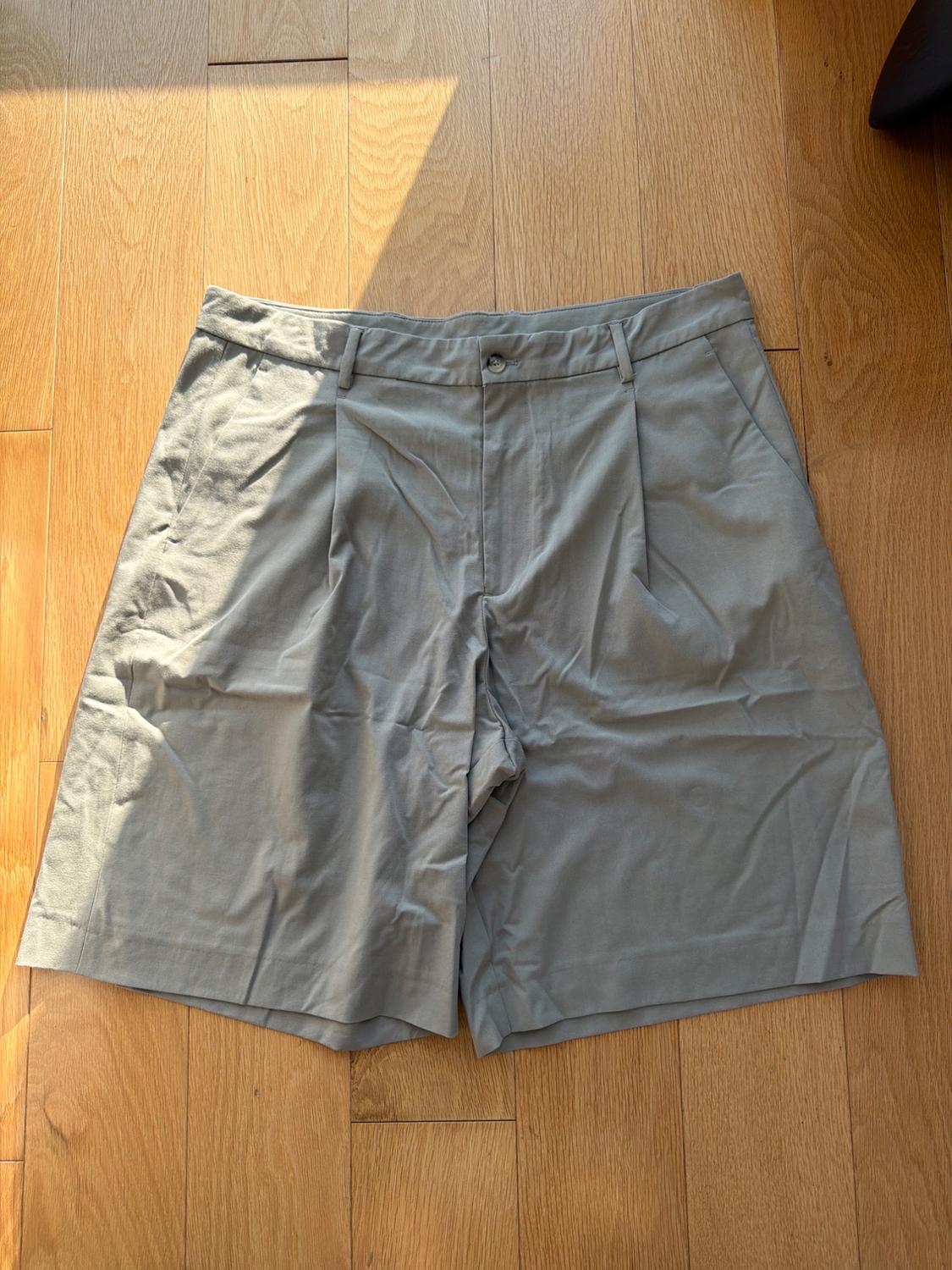 Wrinkled gray shorts on a light wood floor, illuminated by natural light from the top left corner.