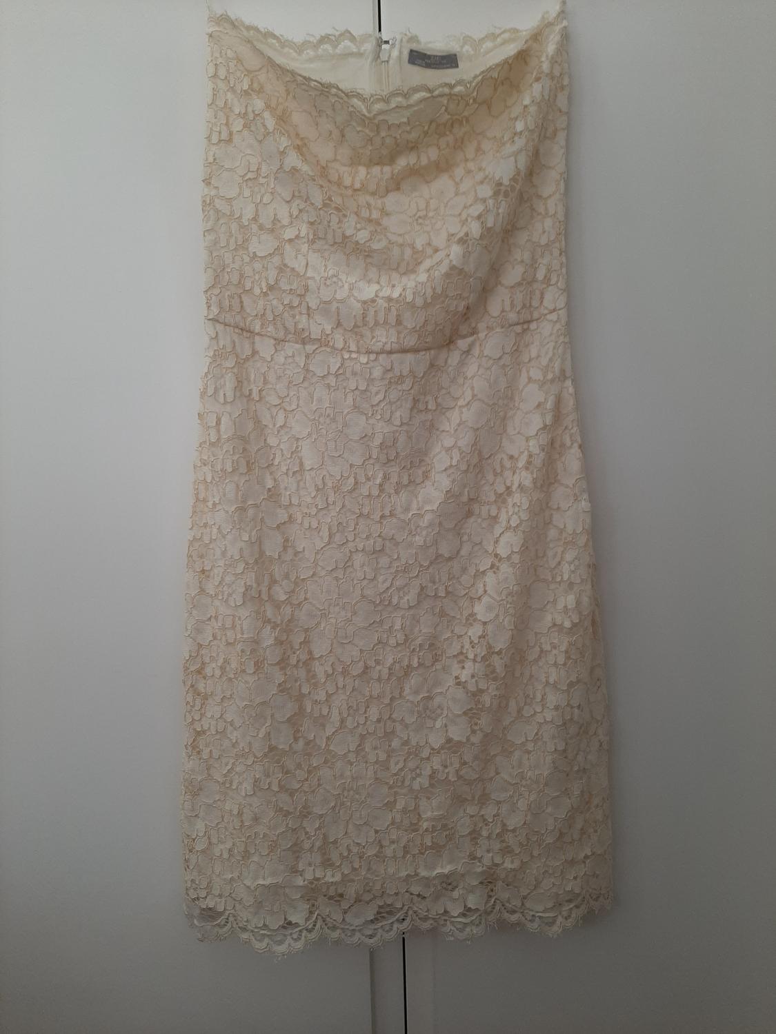 Front view of a beige lace dress with a straight neckline and no sleeves.