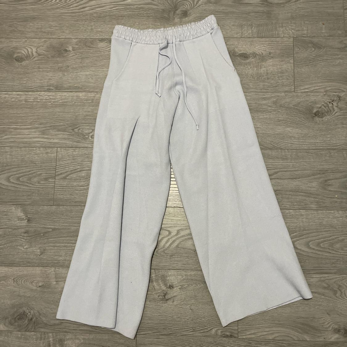 Light grey wide-leg trousers with an elasticated drawstring waist, on a grey wooden floor.