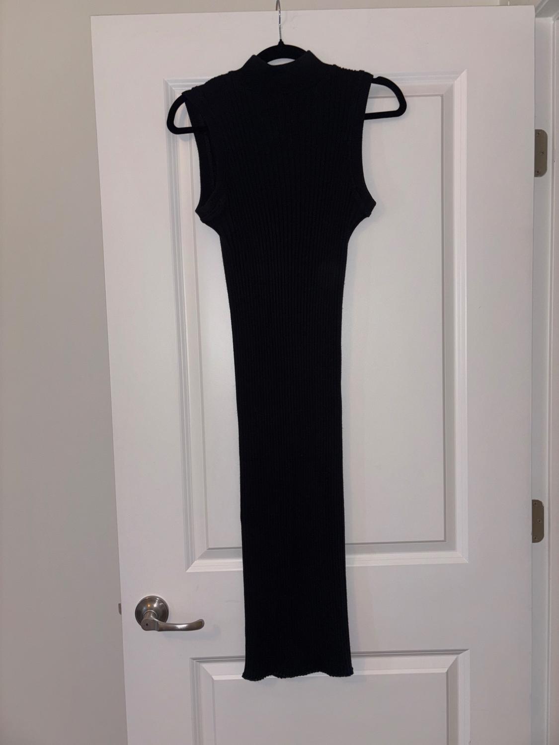 Sleeveless black ribbed knit dress hanging on a white door with a metal doorknob.