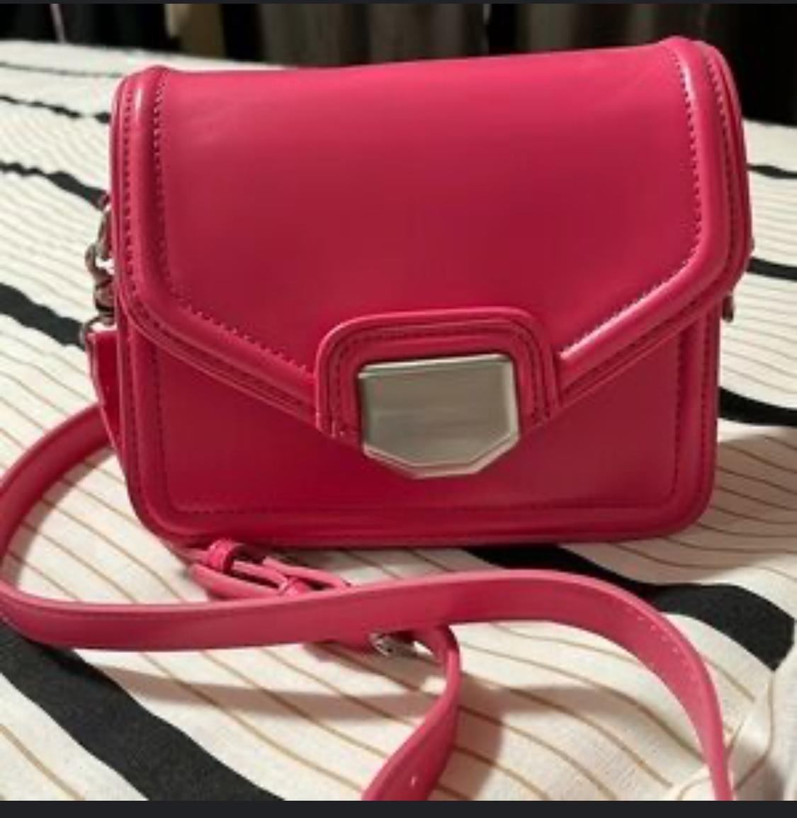 Close-up of a pink handbag with a metal clasp and adjustable strap.