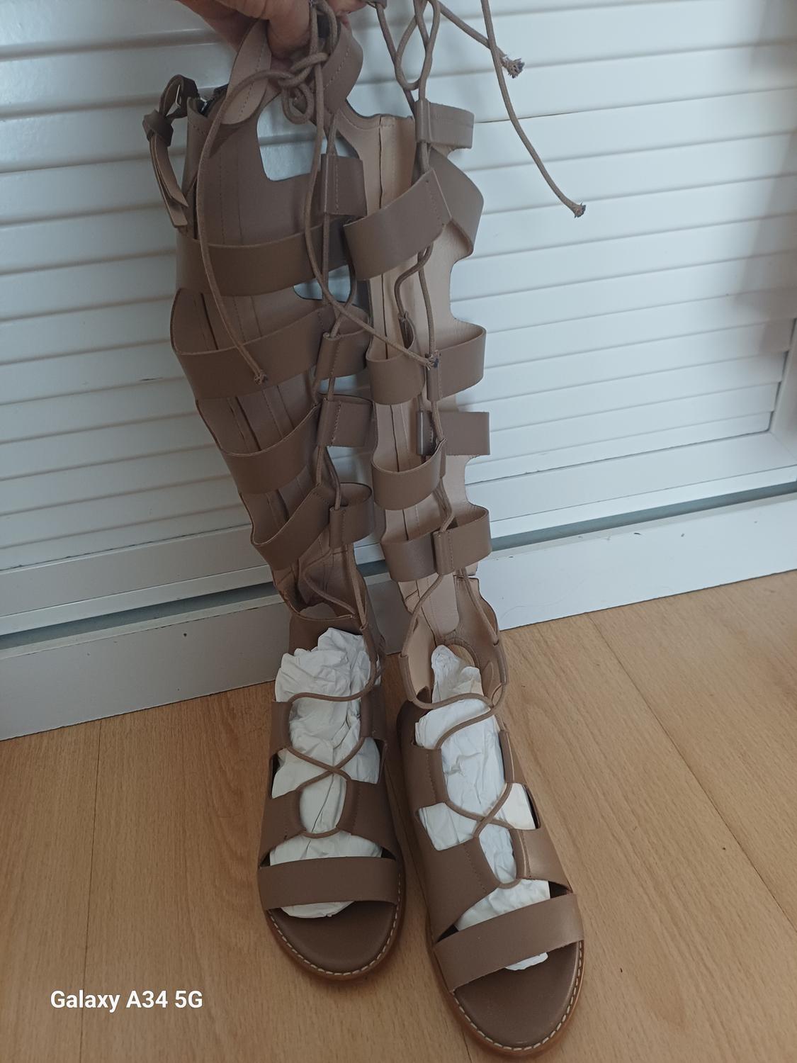 Front view of brown high-heeled sandals with straps and a flat heel, with paper stuffing inside.