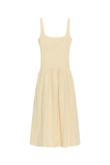 Front view of a raw midi dress with a square neckline, wide straps, and texture. Flared hem.