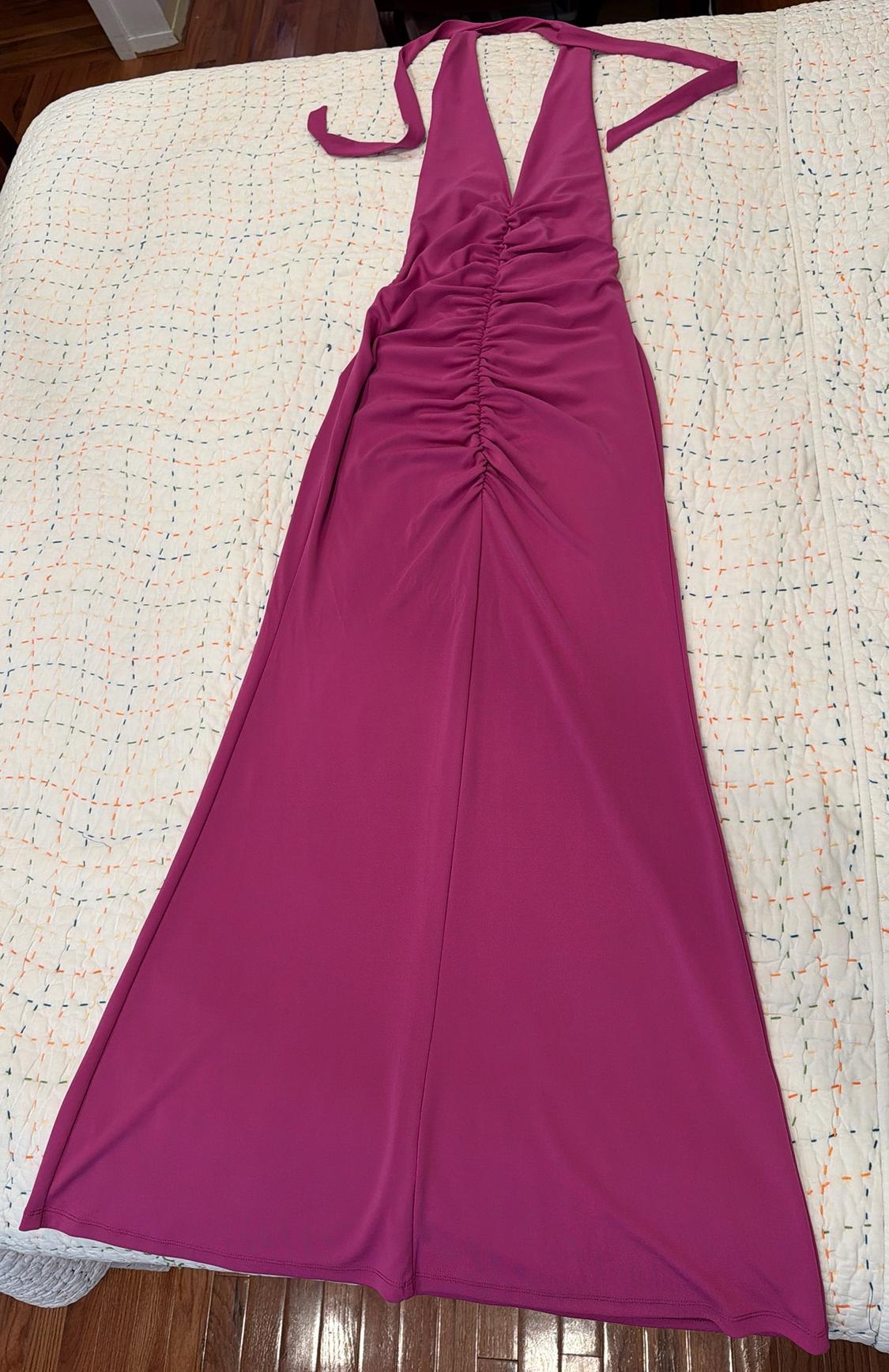 Magenta maxi dress with a halter neck, V-neck, and center ruching, laid out on a bed with a white bedspread.