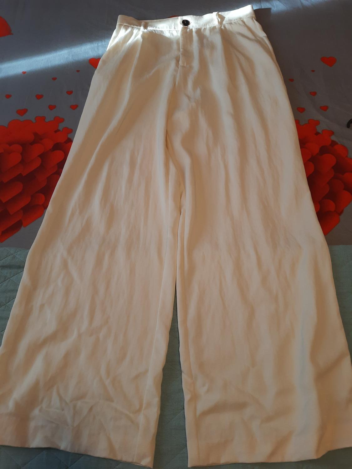 Front view of white trousers with a front button and wide leg.