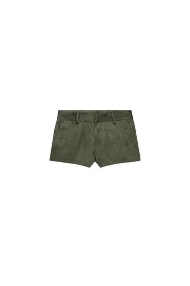 Front view of moss green mini shorts with a mid-rise waist, belt loops, front pockets and patch pockets on the back. Fastening with zip and button.
