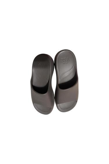Black rubber sandals viewed from above, with the "ZARA" brand and size "39-40" engraved on the insole. White background.