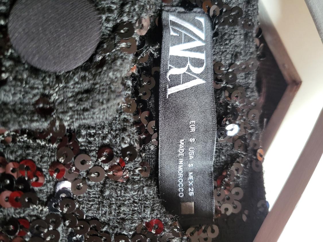 ZARA label with the text 'EUR S USA S MEX 26 MADE IN MOROCCO' on a dark garment with black sequins and a button.