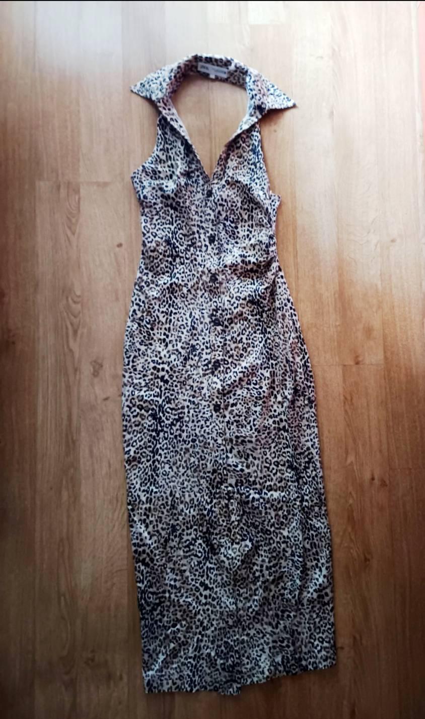 Sleeveless leopard print maxi dress with a halter neck and front buttons, laid out on a wooden floor.