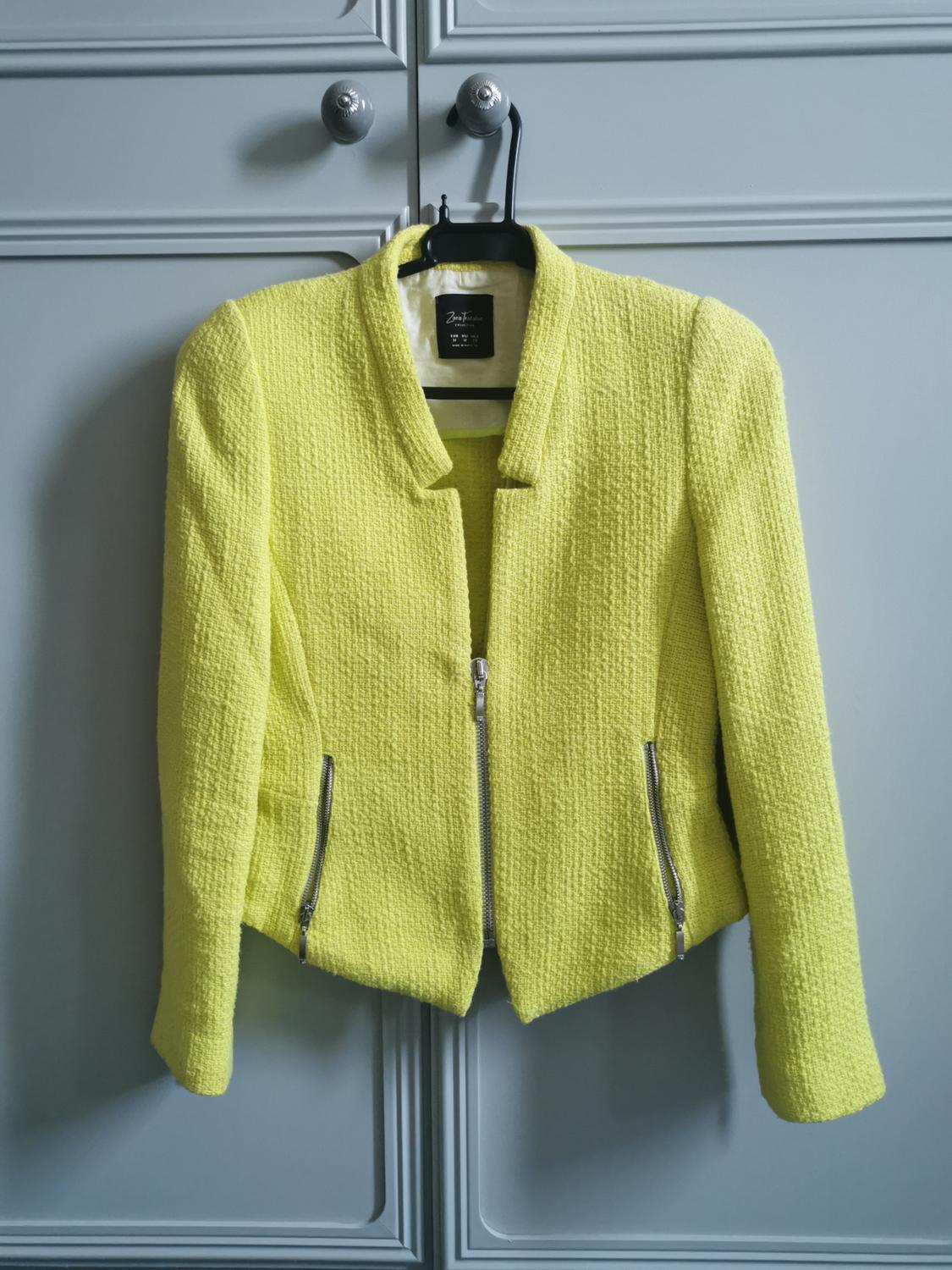 Front view of a yellow jacket with a zip and side pockets.