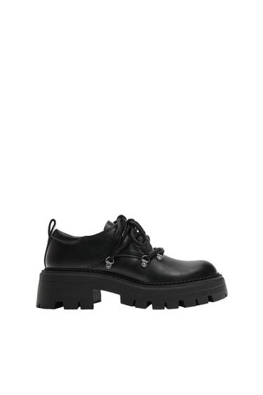 Side view of a black shoe with chunky sole and laces.