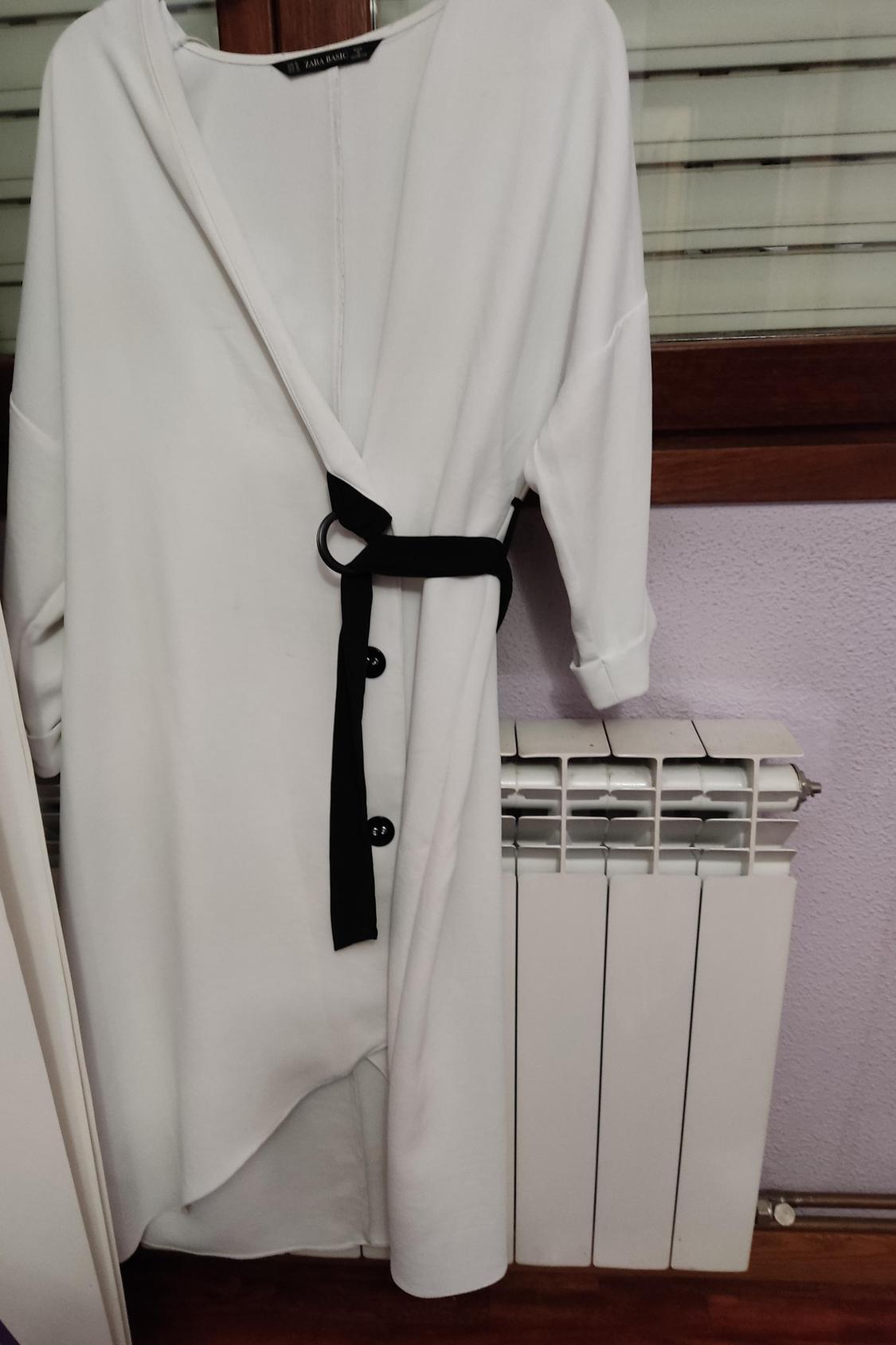 Front view of a white dress with a black belt and decorative buttons.