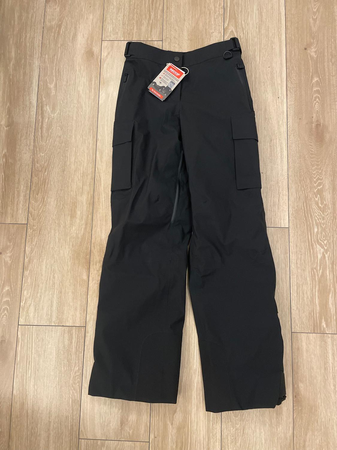 Black cargo trousers on a light wooden floor, with a red and white tag that says "Recco" hanging from the belt.