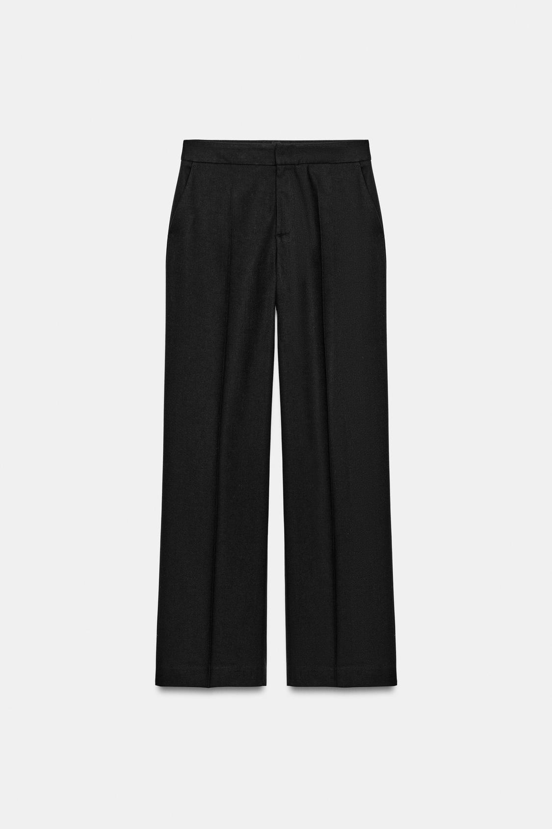 "Sprednji pogled na ravne črne hlače s sprednjimi žepi in lažnimi zadnjimi žepi. Zapiranje spredaj z zadrgo in gumbom."