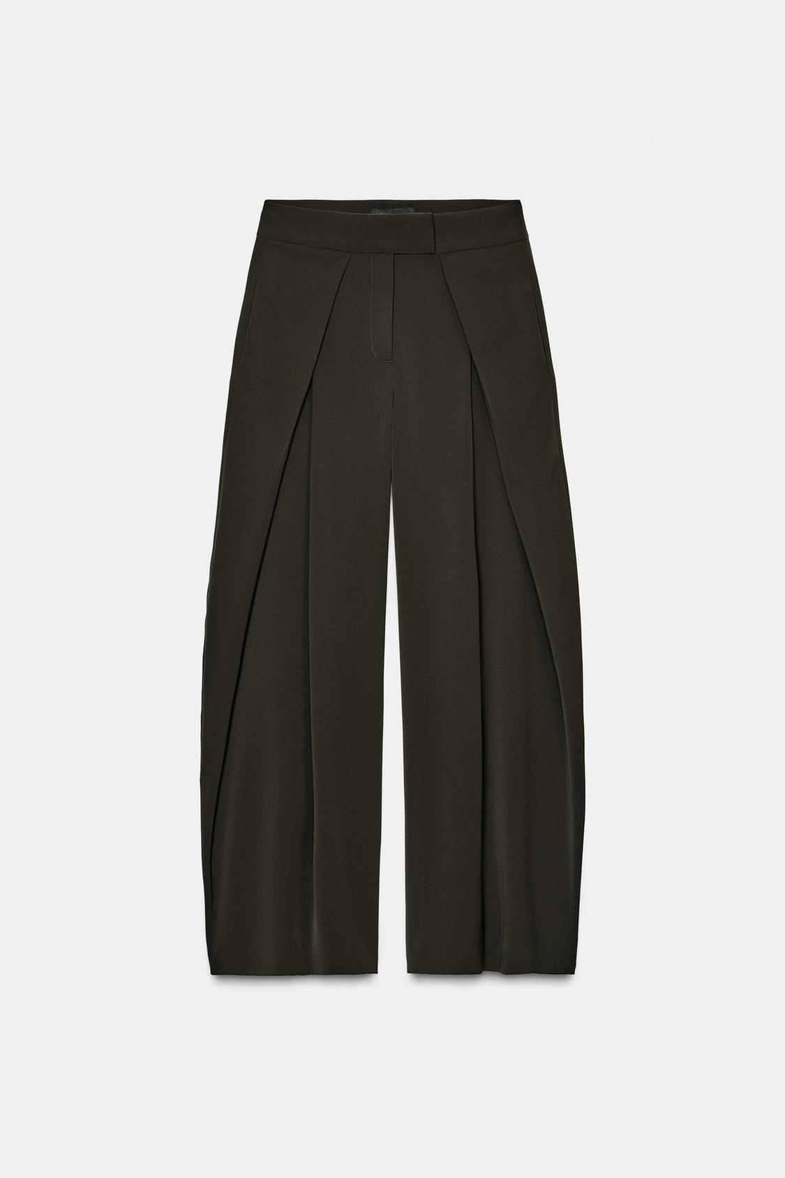Front view of fluid green trousers with pleats and concealed side pockets. Side fastening with concealed zip.