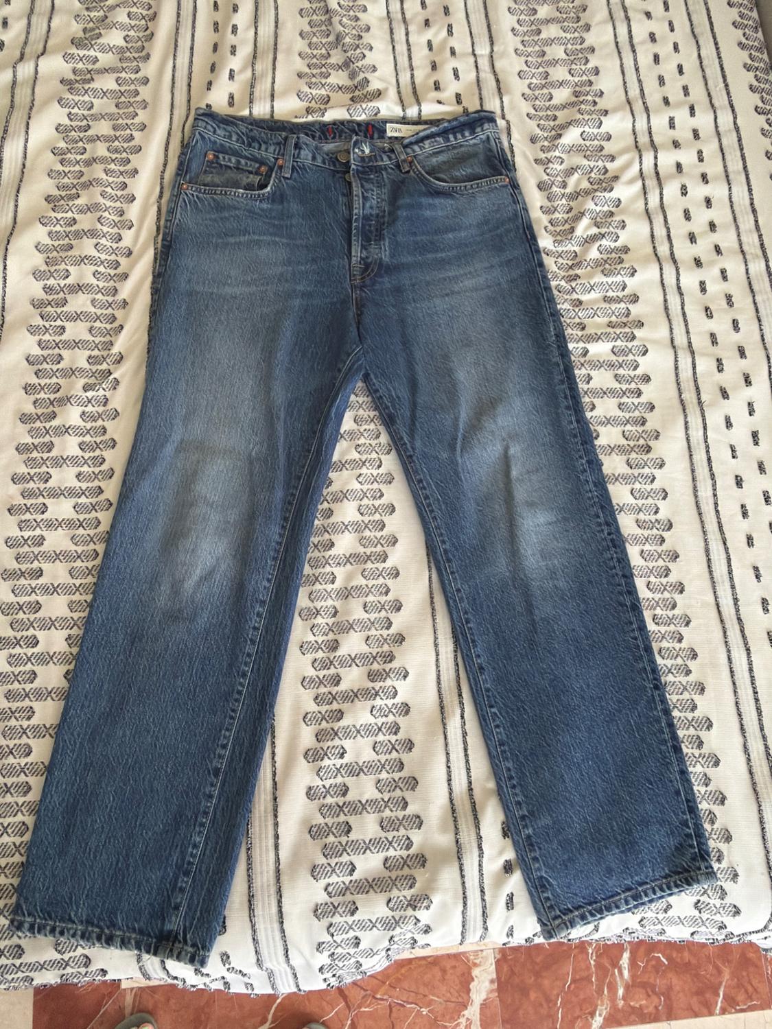 ZARA blue washed-effect jeans, on a white blanket with a black print. Casual and relaxed style.