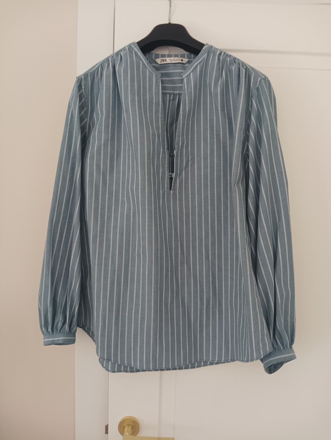 Blue and white striped shirt hanging on a black hanger over a white door.