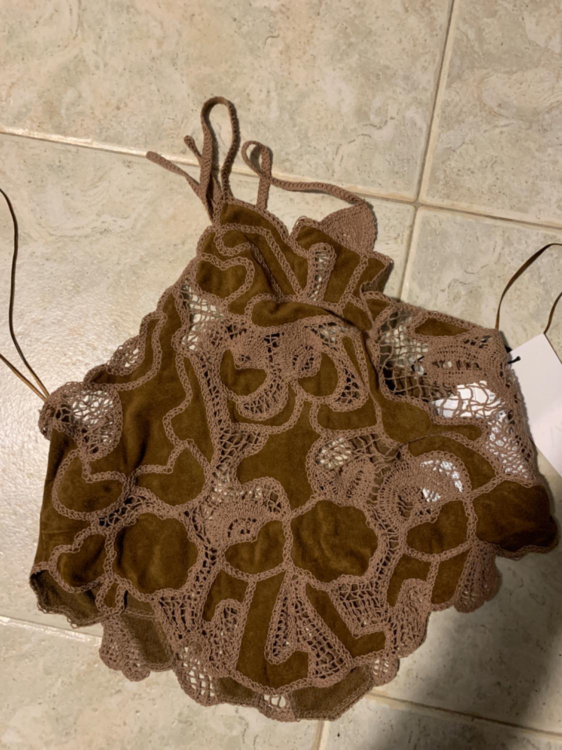 Brown top with beige lace on a light tiled background. Intricate design with thin straps.