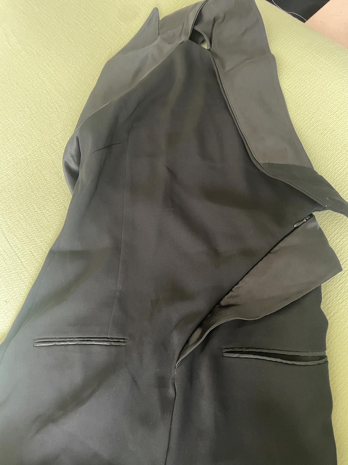 Elegant black suit on a green surface, showing pocket and lapel details.