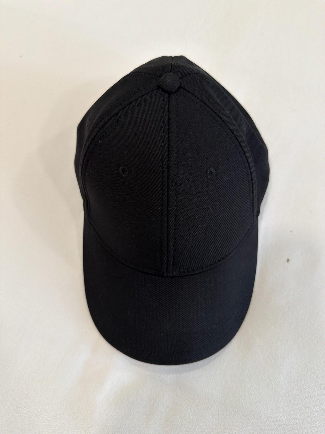 Plain black cap seen from above on a white background. Simple and minimalist composition.