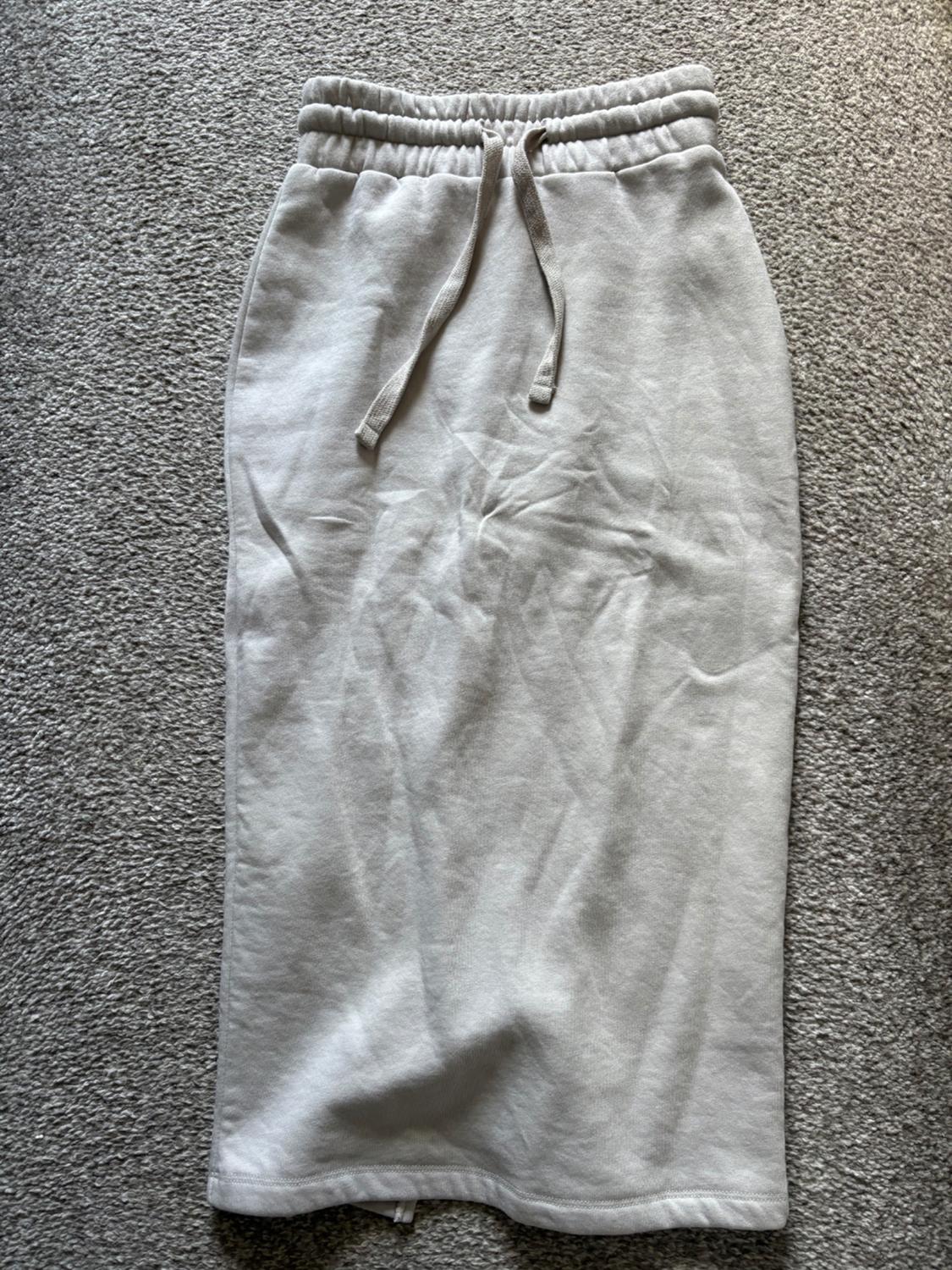 Light grey midi skirt with elasticated waistband and adjustable drawstring, on a grey carpet. Visible wrinkled fabric.