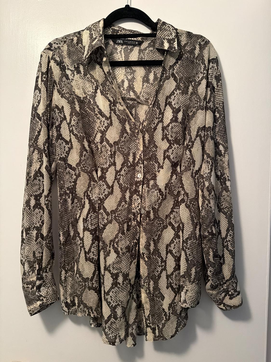 Long-sleeved shirt with snake print in brown and beige tones, hanging on a black hanger against a white background.