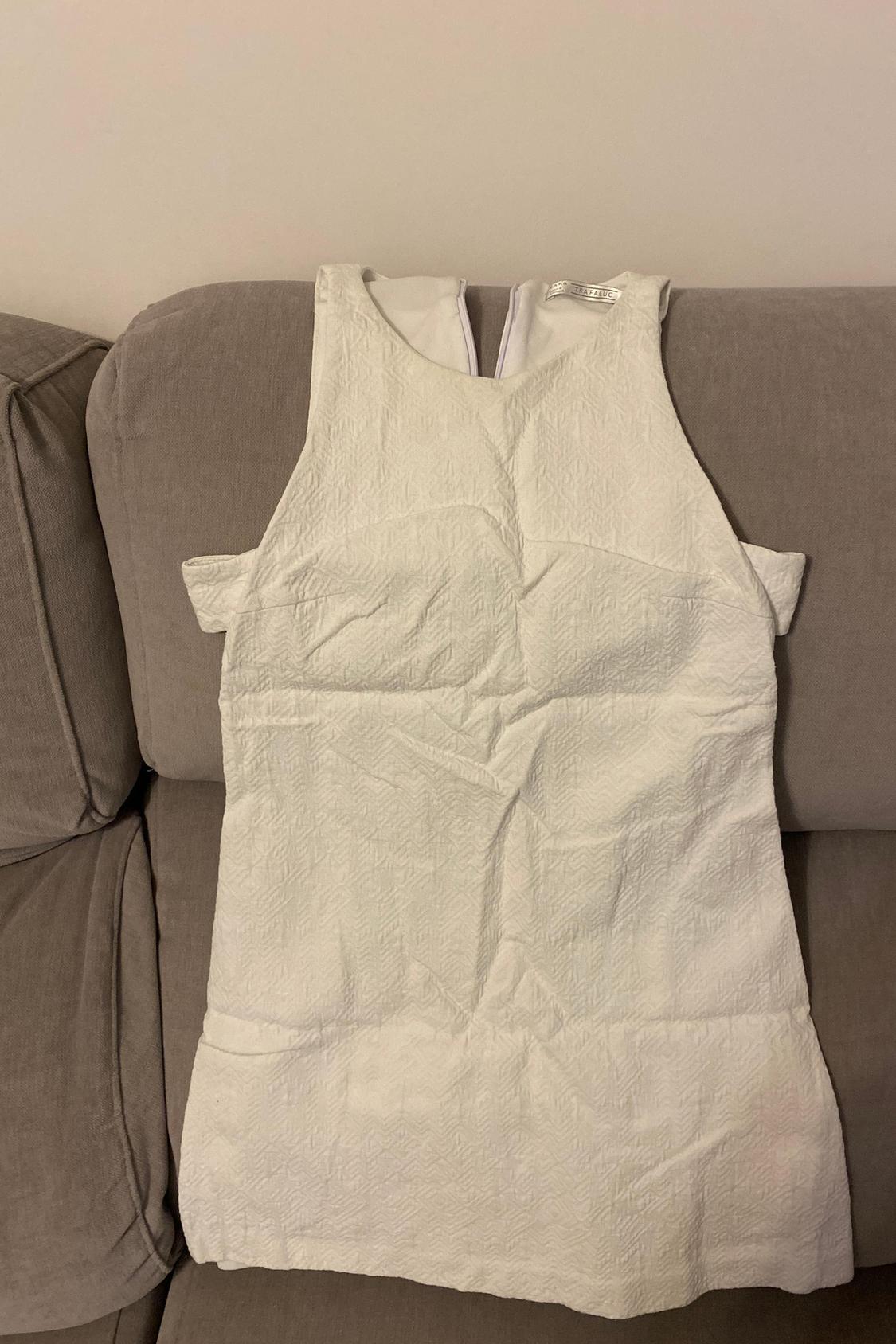 Front view of white sleeveless textured dress, visible back fastening.