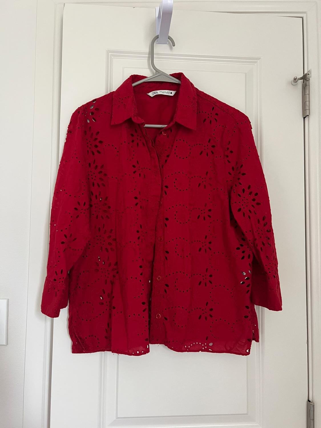 Front view of a red blouse with a cutout design and front buttons.
