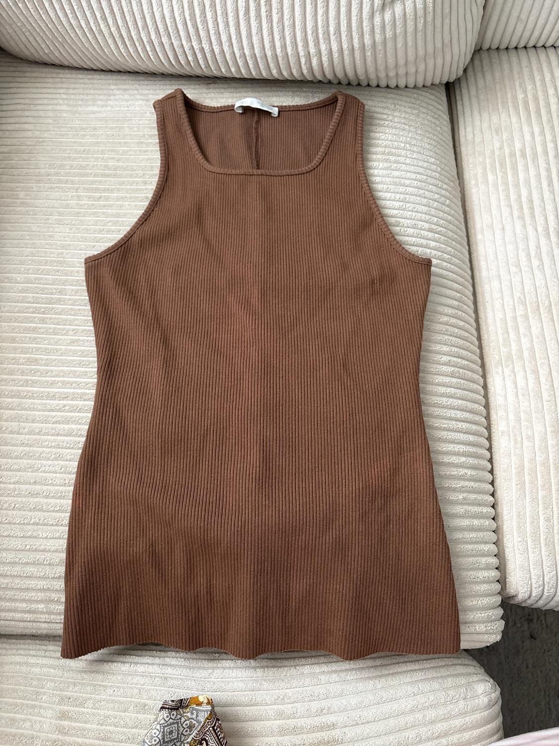 Brown ribbed sleeveless top arranged on a light-coloured surface with a ribbed texture.