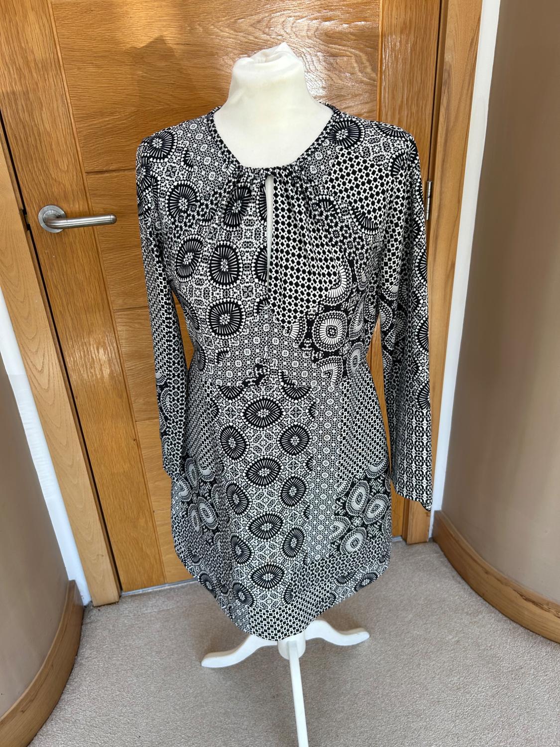 Front view of a black and white printed dress with long sleeves and a geometric design.