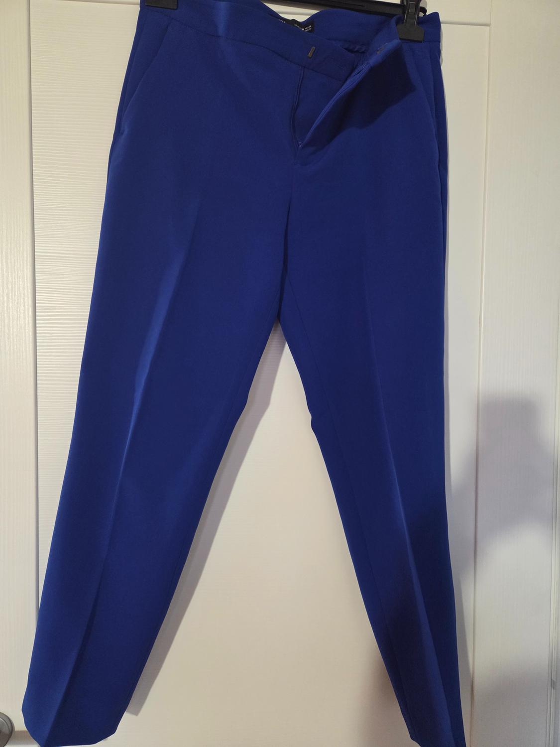 Deep blue trousers hanging on a hanger over a white door, showcasing a classic and elegant design.