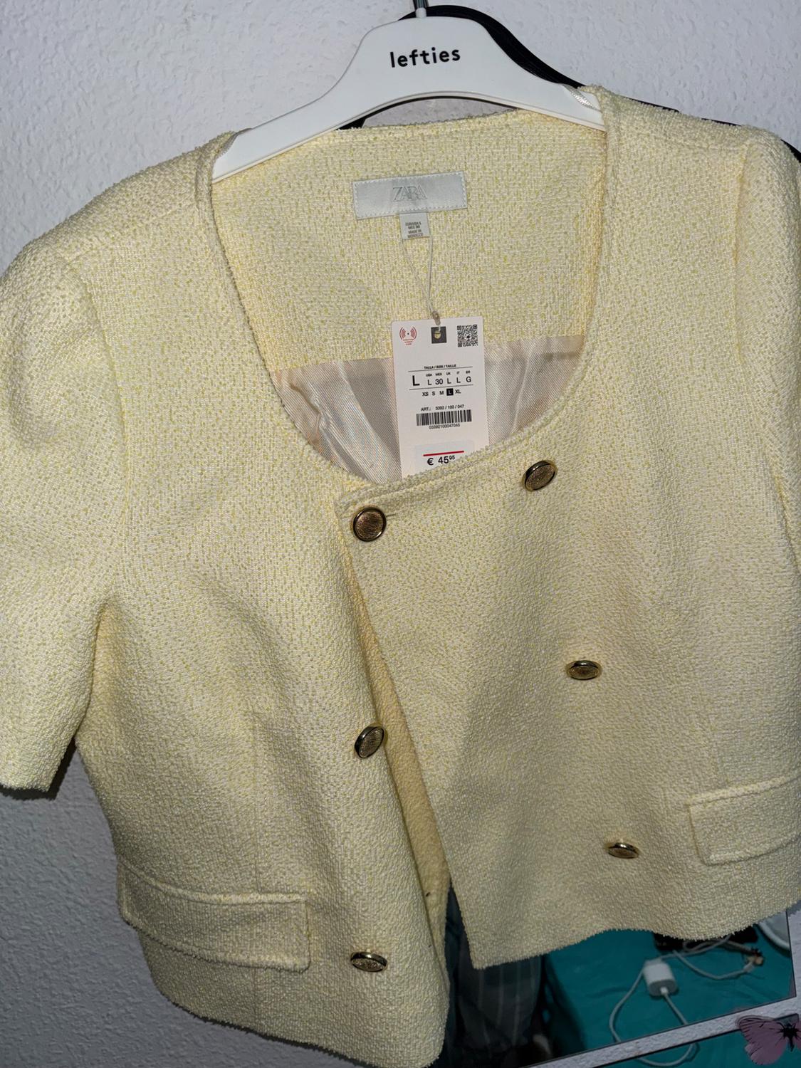 Yellow short-sleeved jacket with gold buttons, hung on a white Lefties hanger. Zara label visible.