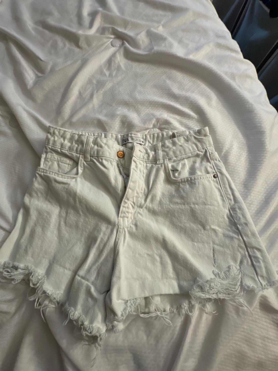 Front view of white shorts with frayed edges and front pockets.