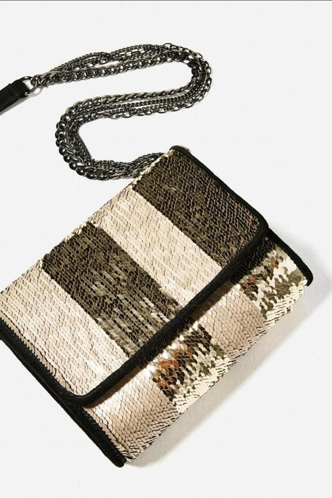 Detail of a black and gold sequin handbag with a metal chain.