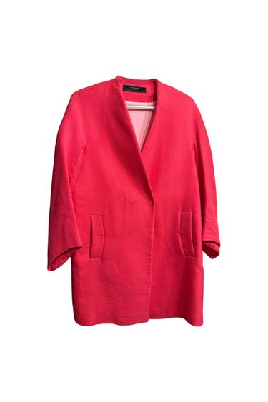 Red long-sleeved coat with an open collar and front pockets, hanging against a white background. Interior label visible.
