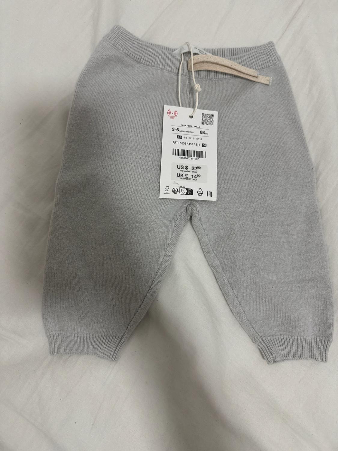 Gray knit pants with drawstring on a white background. Label: SIZE 3-6 MONTHS 68 CM US $ 22.90 UK £ 14.99.