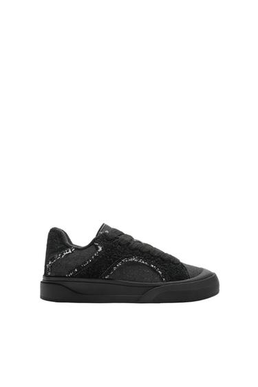 Side view of a black trainer with textured detailing.