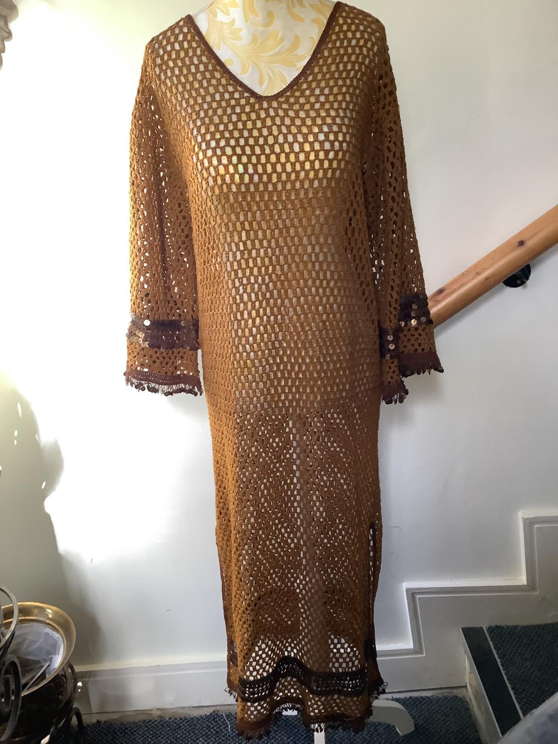 Brown crochet dress with long sleeves and dark detailing on the cuffs and hem, displayed on a mannequin.